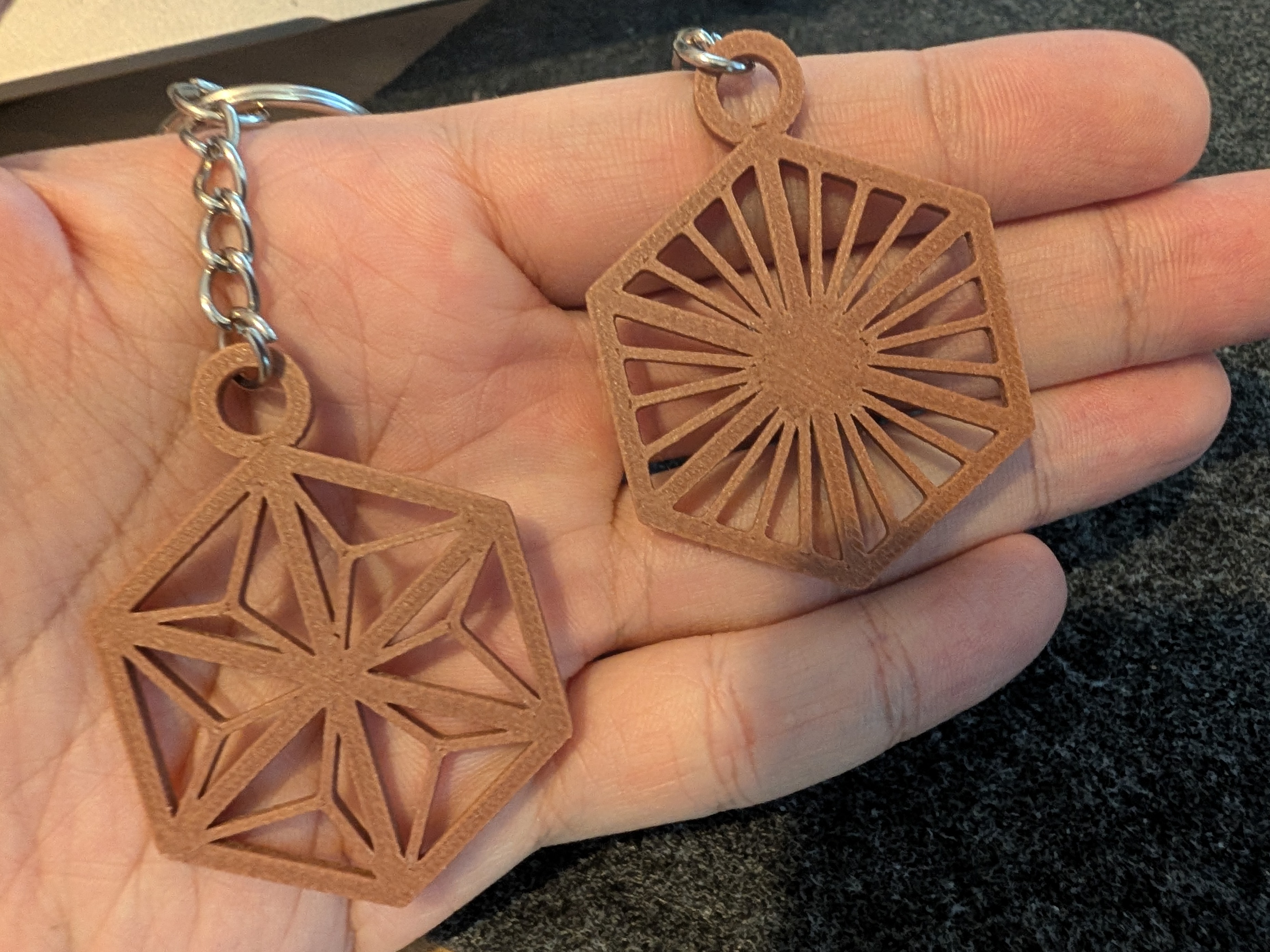 3D printed Kumiko keychain in wood-infused filament held alongside the felt mascot